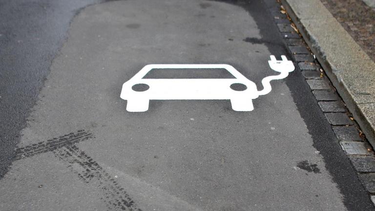 Das Symbol eines Autos mit Kabel auf dem Asphalt - ein Parkplatz für Elektroautos. Das Symbol eines Autos mit Kabel auf dem Asphalt - ein Parkplatz für Elektroautos.