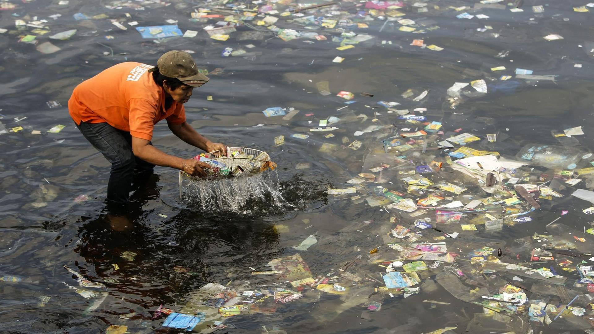 Ein Müllsammler fischt Plastiktüten aus der Bucht von Manila. Anlass war der 5. internationale plastikfreie Tag.