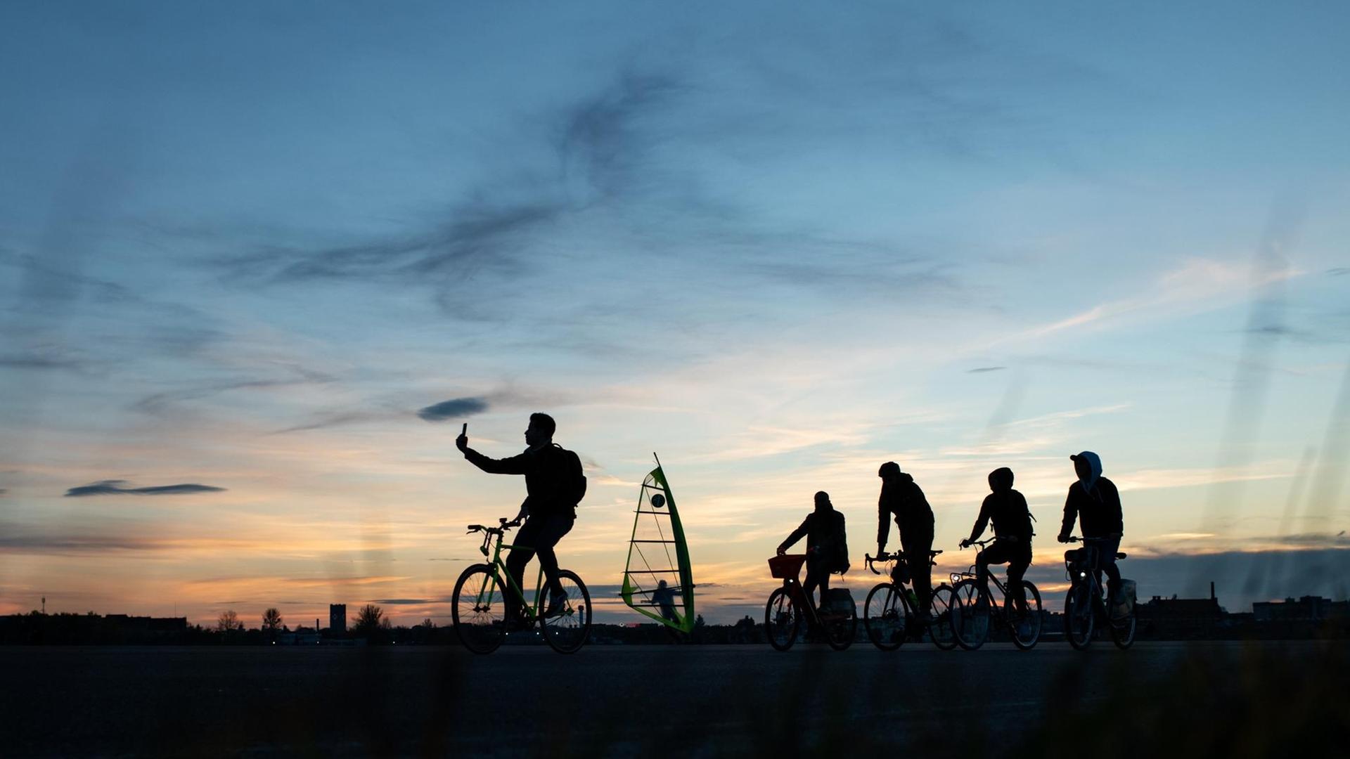 Schattenrisse gegen Abendhimmel: Besucher sind auf dem Tempelhofer Feld in Berlin unterwegs. Schattenrisse gegen Abendhimmel: Besucher sind auf dem Tempelhofer Feld in Berlin unterwegs.