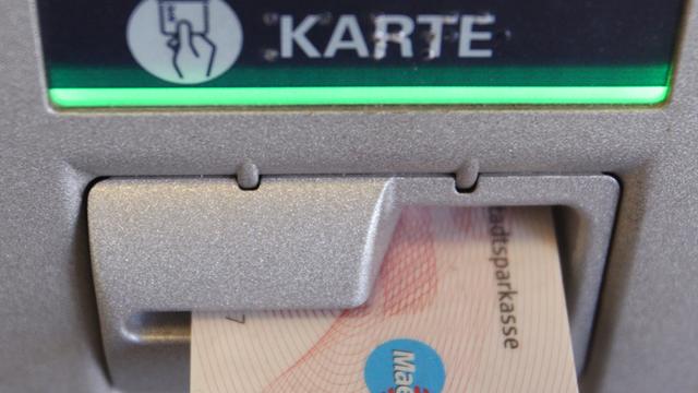 Eine EC-Karte steckt im Schlitz eines Geldautomaten
