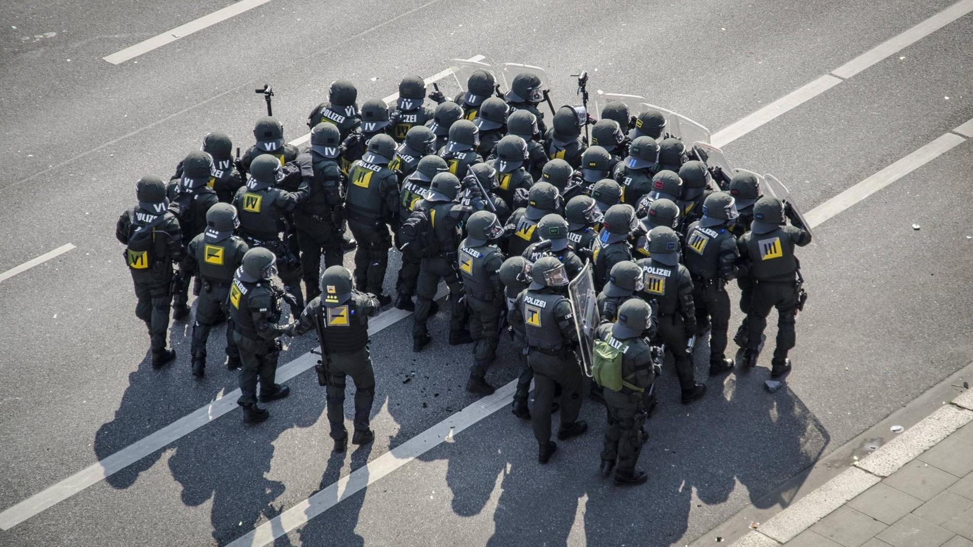 Vogelperspektive auf eine Gruppe von Polizisten mit Schilden die sich zu einer Gruppe formiert haben. Vogelperspektive auf eine Gruppe von Polizisten mit Schilden die sich zu einer Gruppe formiert haben.