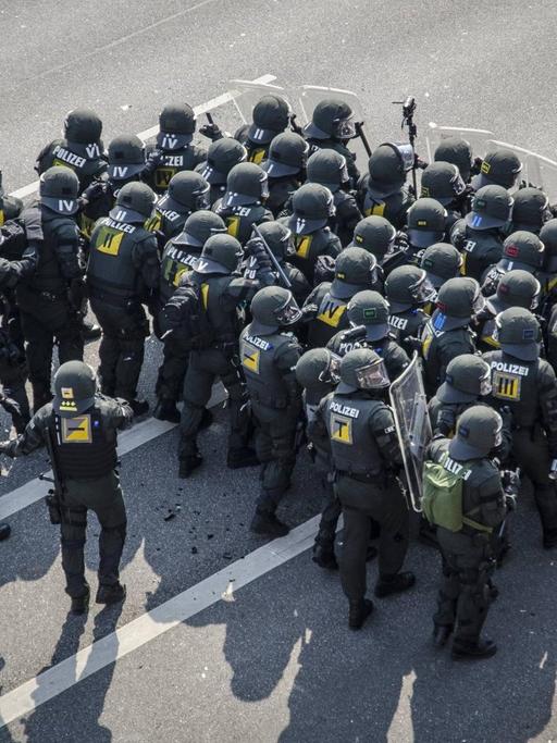 Vogelperspektive auf eine Gruppe von Polizisten mit Schilden die sich zu einer Gruppe formiert haben.