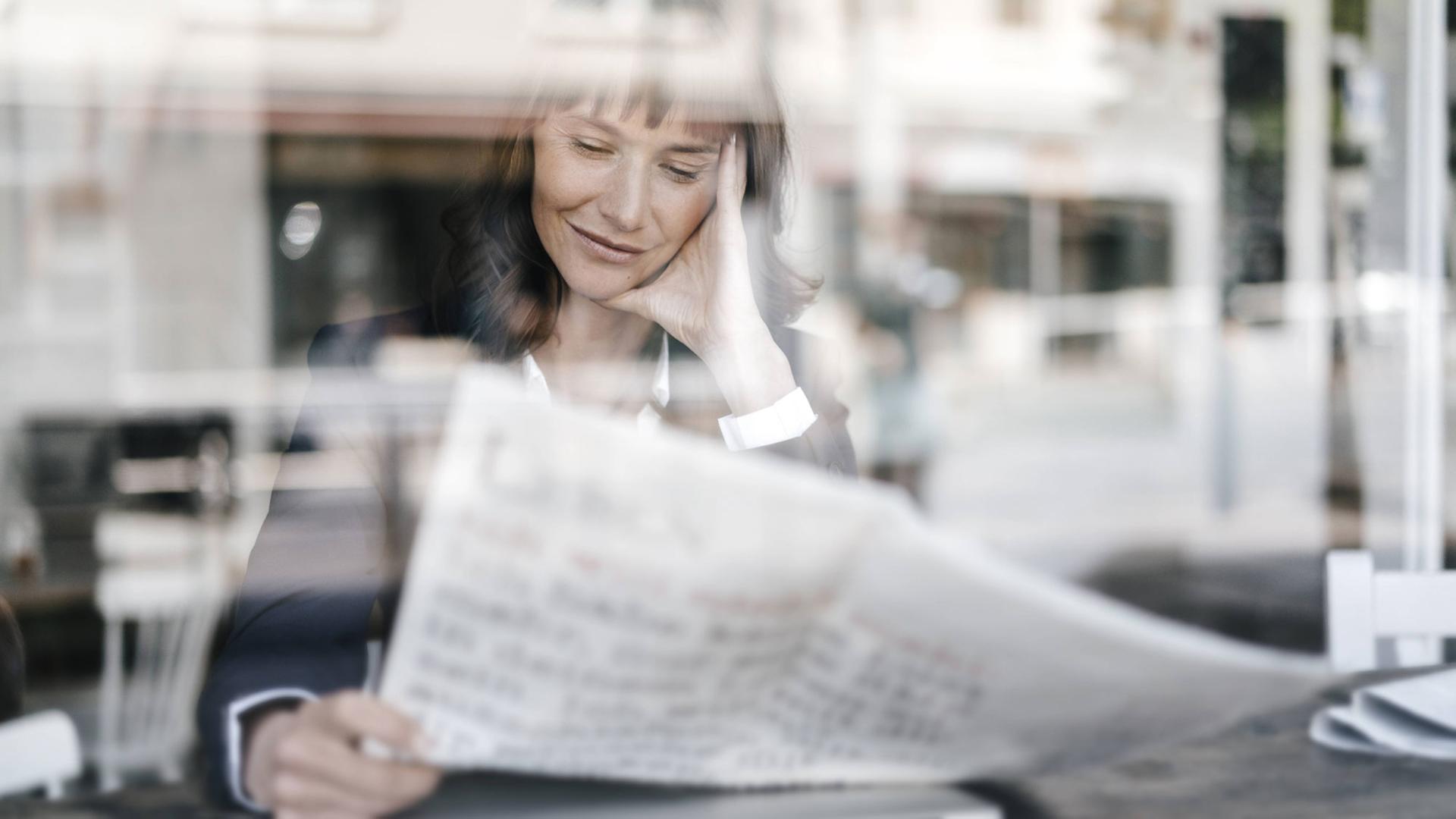 Frau liest Zeitung in einem Café Frau liest Zeitung in einem Café