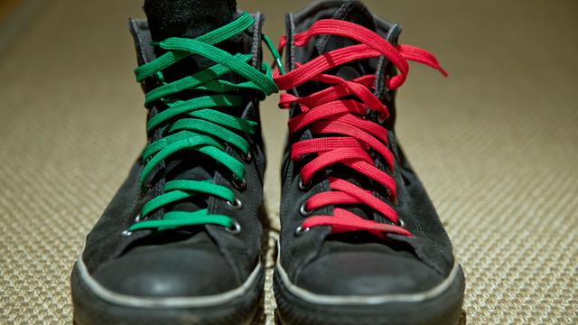  Ein paar schwarze Schuhe mit einem grünen und einem roten Schürsenkel. (c) picture alliance / dpa / Daniel Karmann