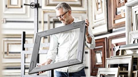 Werner Murrer in seinem Atelier mit einem Bilderrahmen in der Hand.