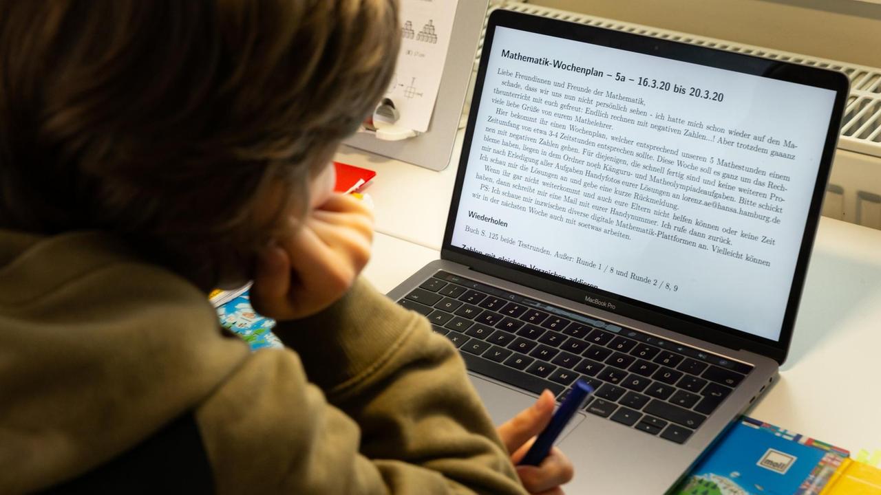 Ein Junge lernt vor einem Laptop.