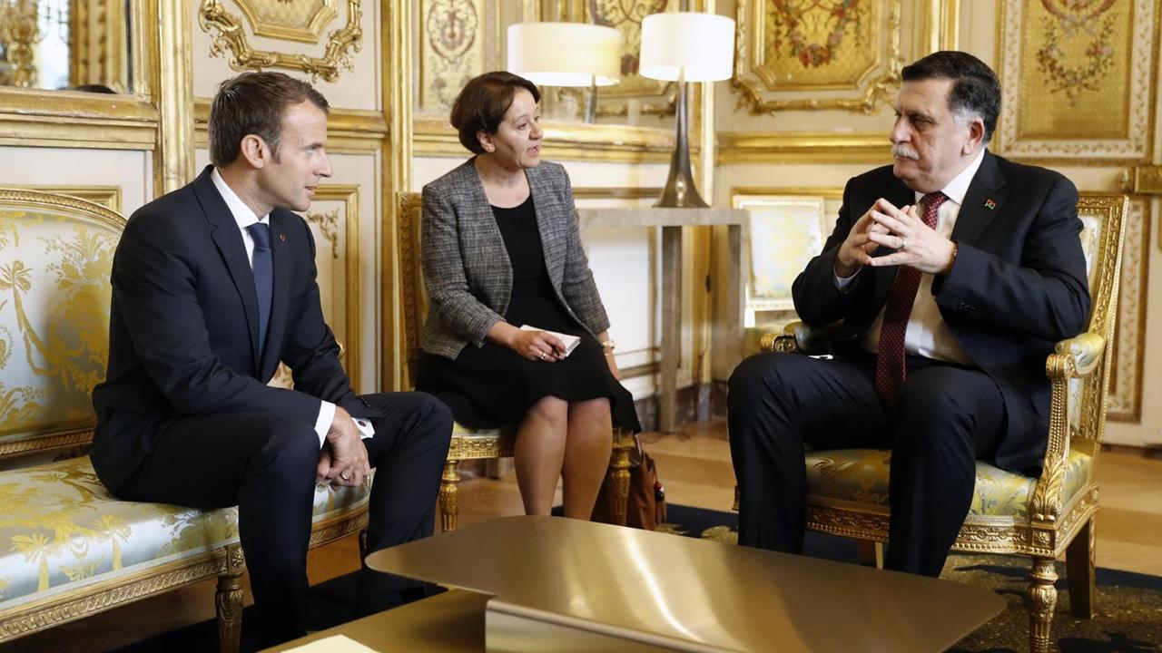 Die drei sitzen in einem goldvertäfelten Saal auf Sesseln. Die Übersetzerin sagt gerade etwas zum libyschen Premier.