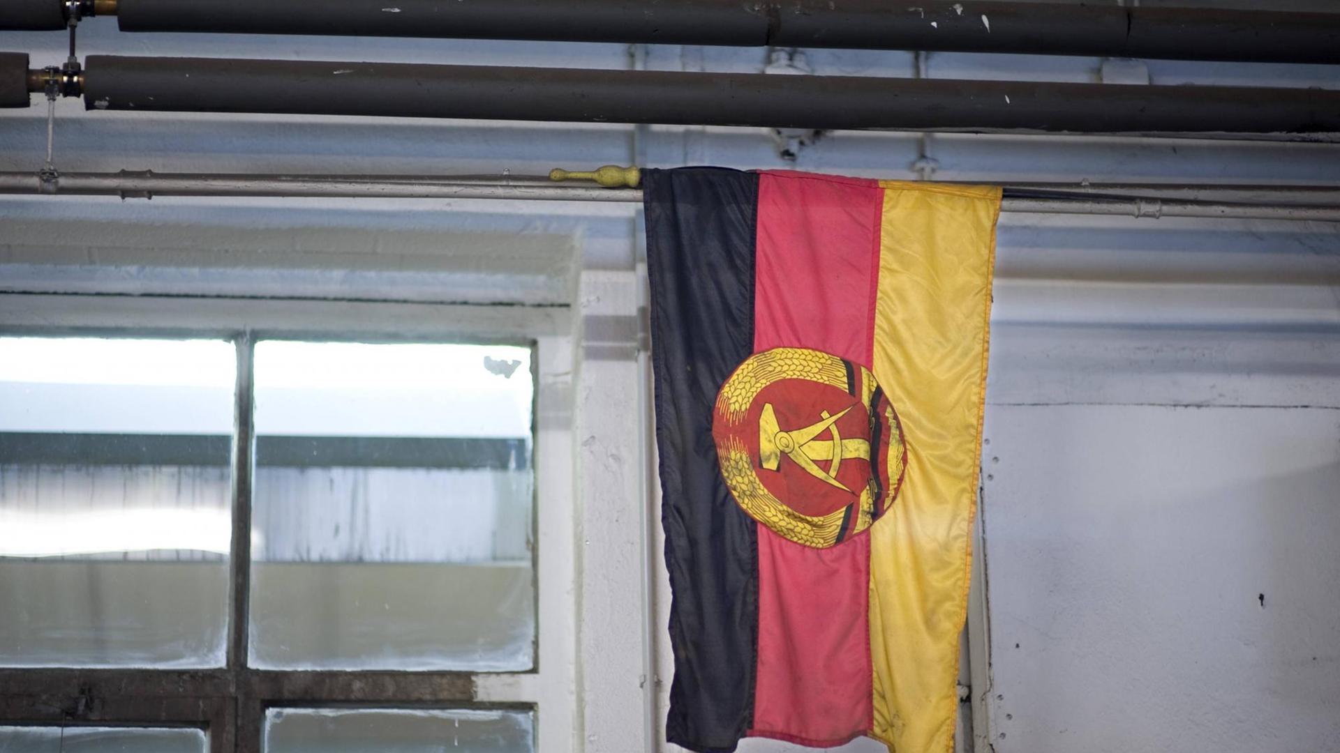 Eine Flagge der ehemaligen DDR hängt in einem Raum mit Fenster. Eine Flagge der ehemaligen DDR hängt in einem Raum mit Fenster.