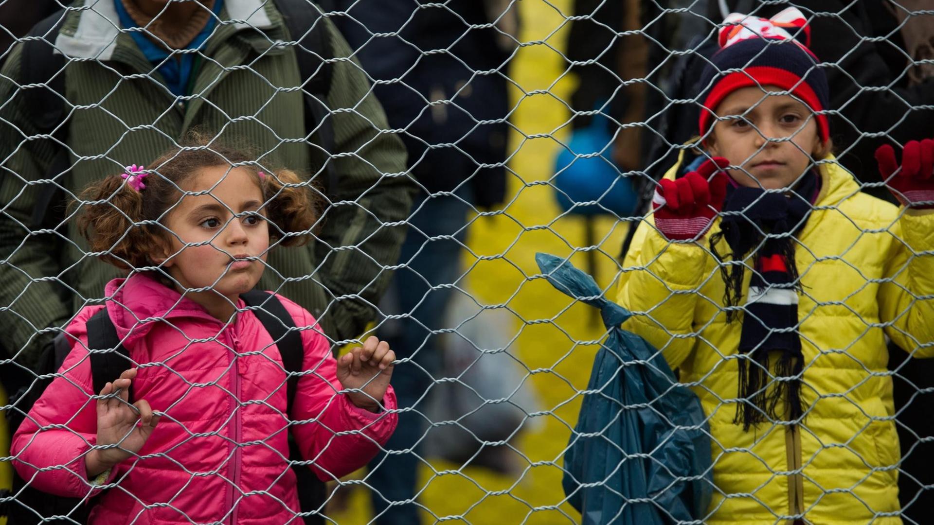 Man sieht zwei Kinder hinter einem Drahtzaun. Man sieht zwei Kinder hinter einem Drahtzaun.
