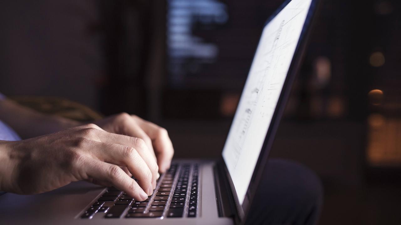 Mann tippt bei Dunkelheit am Computer Mann tippt bei Dunkelheit am Computer