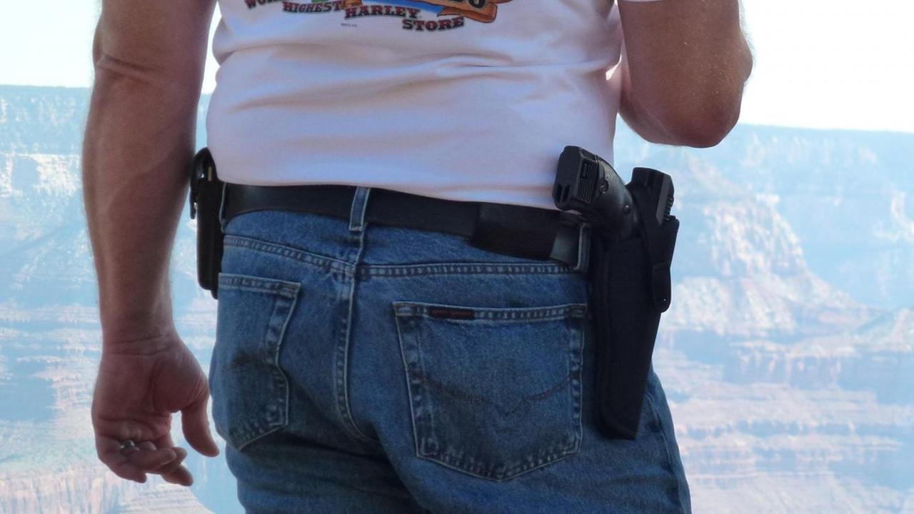Ein Mann steht am 06.09.2013 am Südrand des Grand Canyon, Arizona, mit seiner Waffe im Halfter neben einer Frau. Das Tragen von Waffen in der Öffentlichkeit ist im US-Bundesstaat Arizona erlaubt. Ein Mann steht am 06.09.2013 am Südrand des Grand Canyon, Arizona, mit seiner Waffe im Halfter neben einer Frau. Das Tragen von Waffen in der Öffentlichkeit ist im US-Bundesstaat Arizona erlaubt.