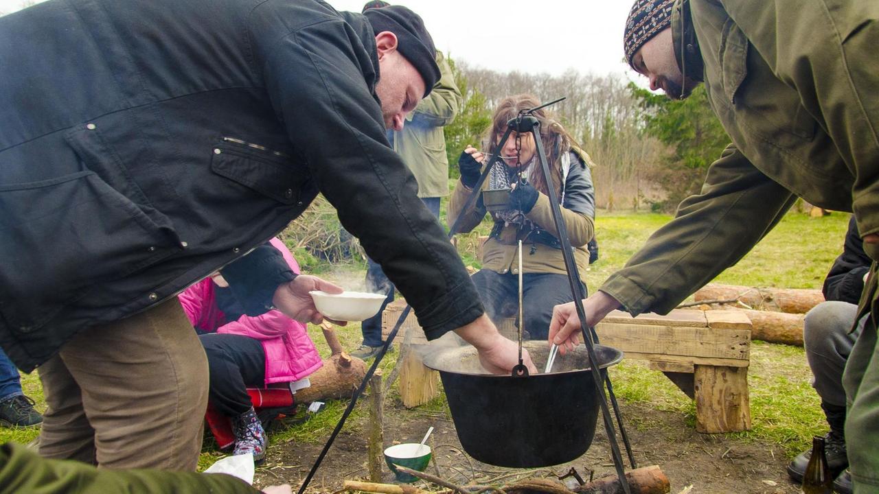 Menschen am Lagerfeuer essen Suppe Menschen am Lagerfeuer essen Suppe