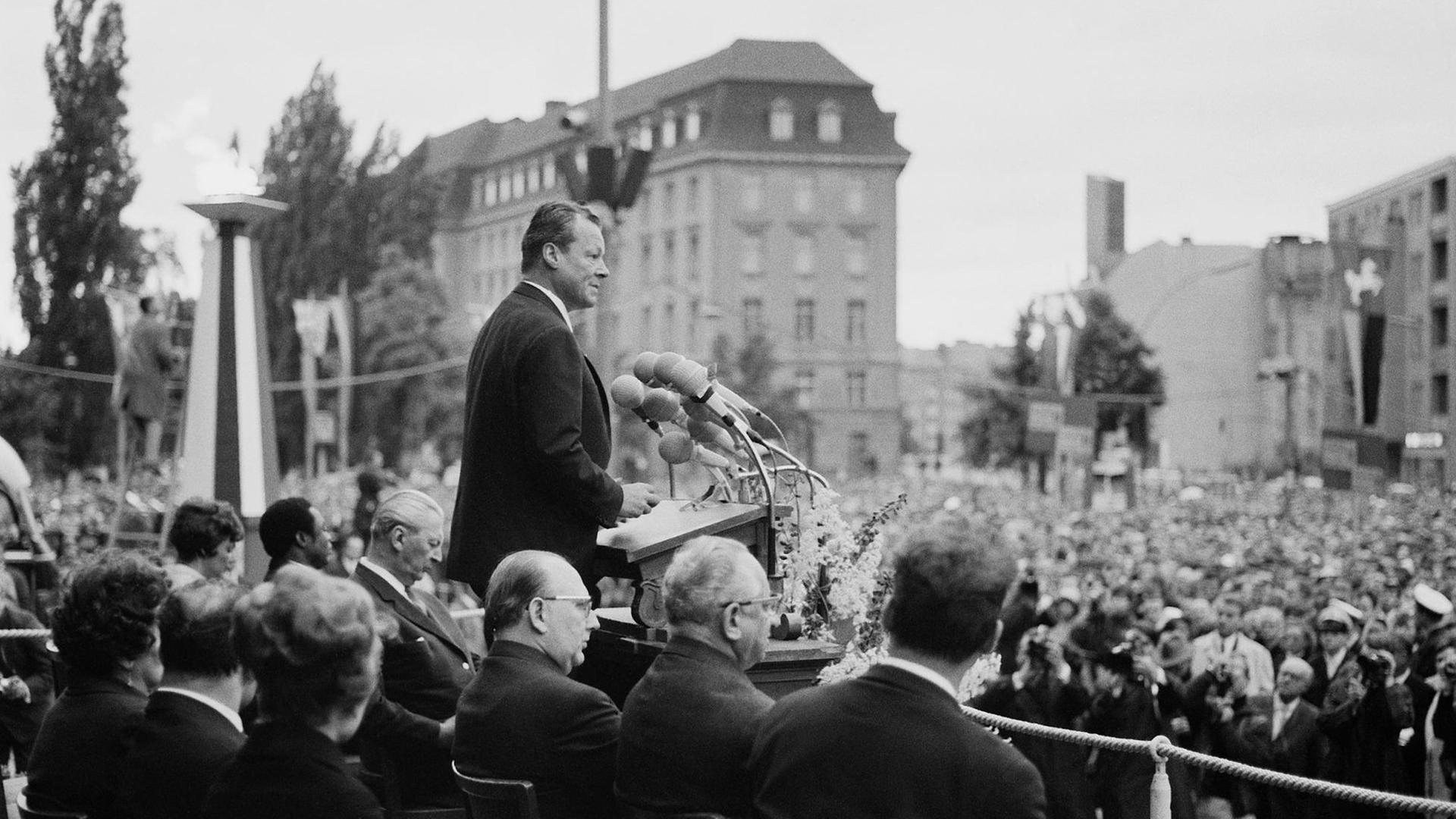 Schwarzweiß-Aufnahme des SPD-Politikers und Regierenden Bürgermeisters von Berlin, Willy Brandt, während seiner Rede zum Tag der Deutschen Einheit am 17. Juni 1965 vor dem Rathaus Schöneberg.