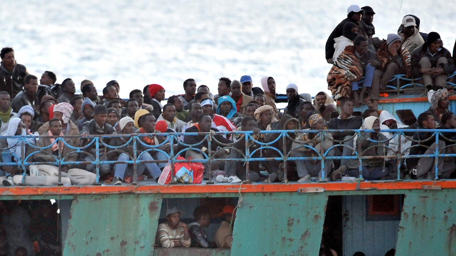 Ein überfülltes Boot mit Flüchtlingen aus Afrika schwimmt vor der italienischen Insel Lampedusa. Ein überfülltes Boot mit Flüchtlingen aus Afrika schwimmt vor der italienischen Insel Lampedusa.