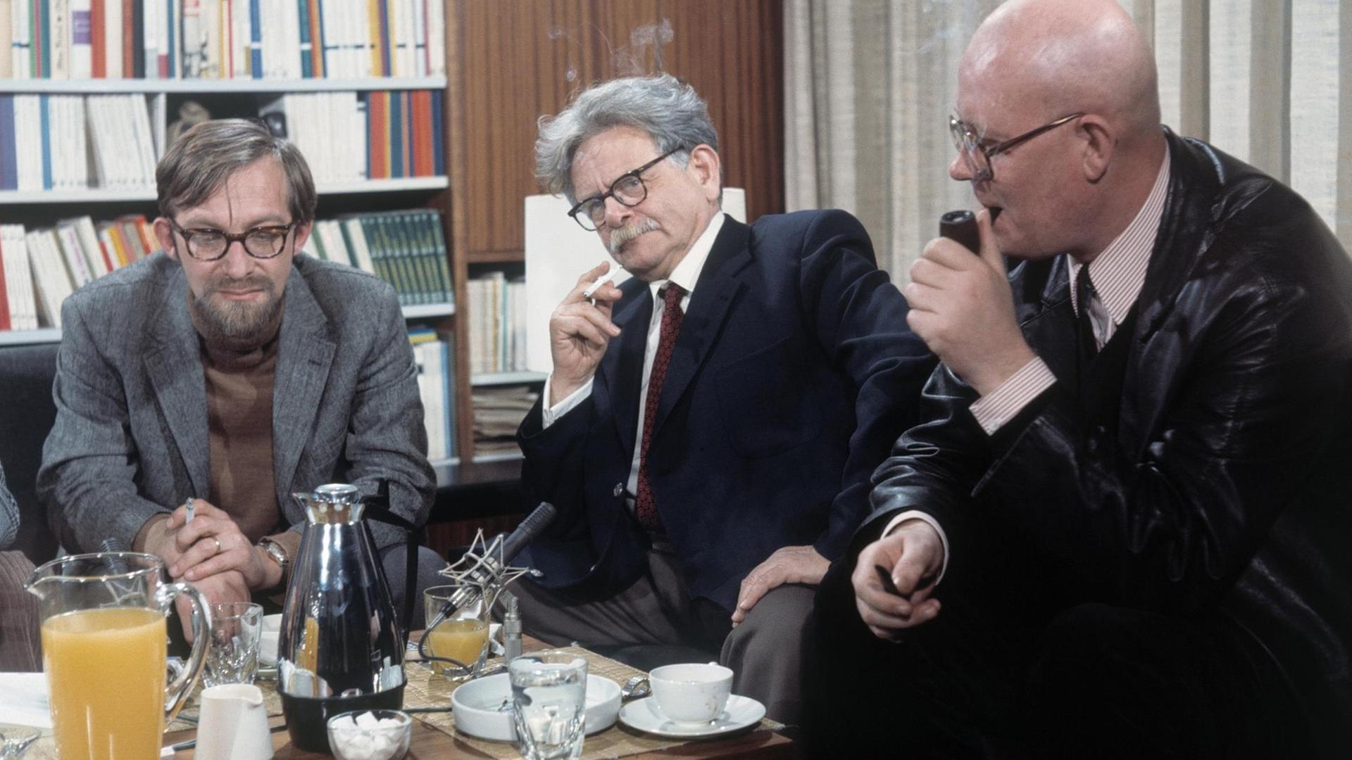 Die Autoren Lars Gustafsson, Elias Canetti und Uwe Johnson (von links) sitzen im Halbkreis um einen Tisch und diskutieren.
