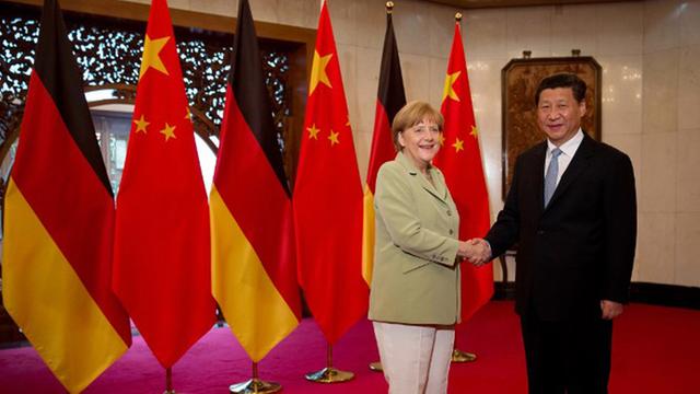 Bundeskanzlerin Angela Merkel und Chinas Präsident Xi Jinping schütteln die Hand. Dahinter stehen mehrere deutsche und chinesische Flaggen.