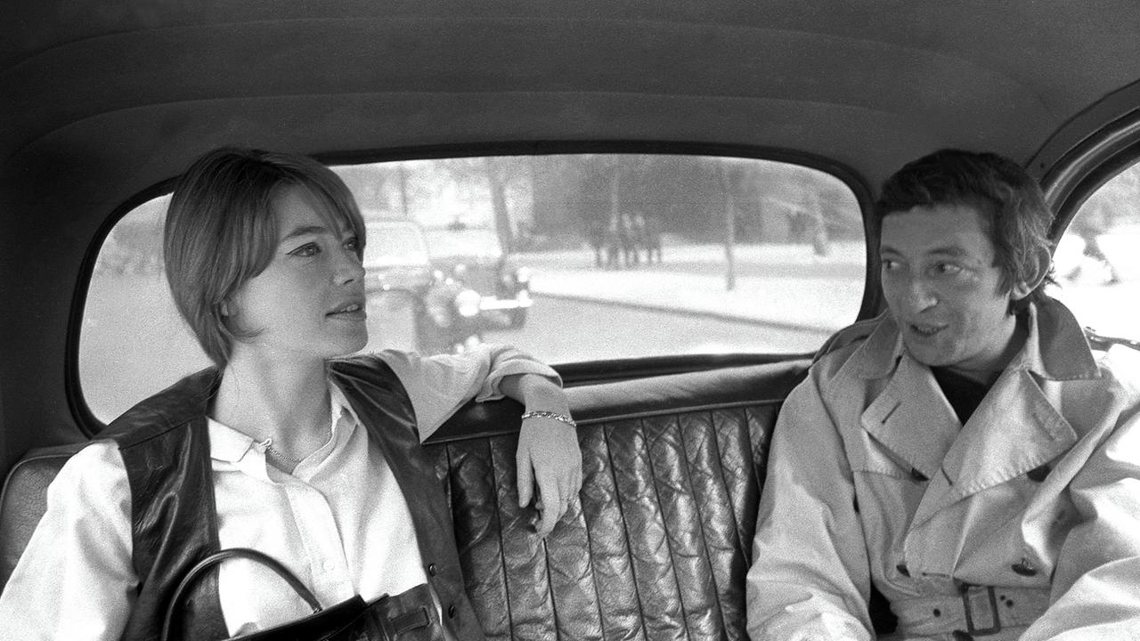 Ein Schwarz-Weiß-Foto zeigt Françoise Hardy, die im Jahr 1969 neben Serge Gainsbourg auf der Rücksitzbank eines Autos sitzt. Ein Schwarz-Weiß-Foto zeigt Françoise Hardy, die im Jahr 1969 neben Serge Gainsbourg auf der Rücksitzbank eines Autos sitzt.
