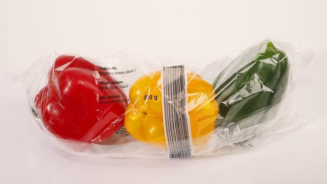 In Plastik eingeschweißter roter, gelber und grüner Paprika aus dem Supermarkt
