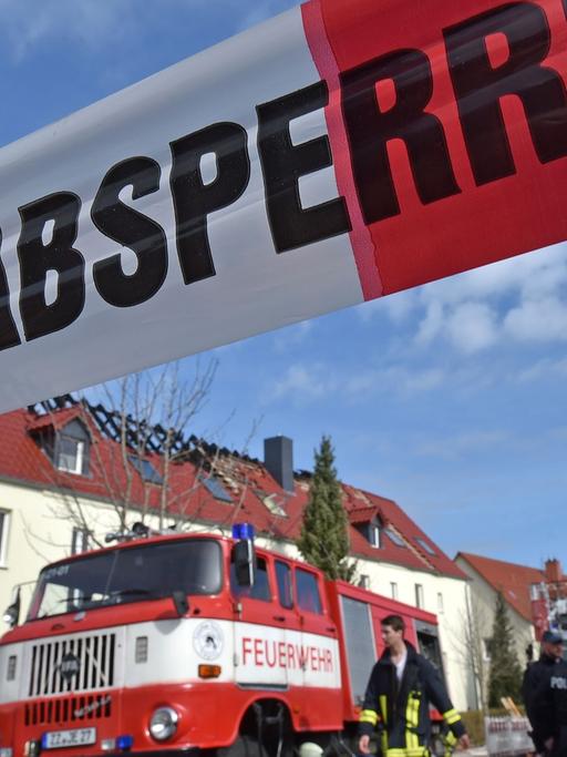 Einsatzkräfte von Feuerwehr und Polizei stehen am 04.04.2015 vor der zukünftigen Unterkunft für Asylbewerber in Tröglitz (Sachsen-Anhalt). In der Nacht hatte es in dem Gebäude gebrannt. Die Polizei ermittelt wegen Verdacht auf Brandstiftung.