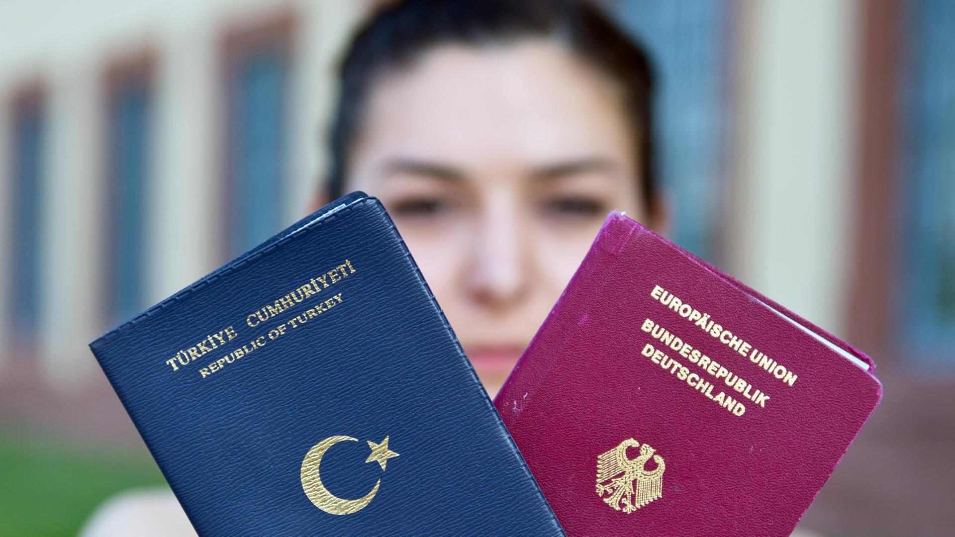 Eine junge Frau hält einen türkischen und einen deutschen Reisepass in den Händen. Eine junge Frau hält einen türkischen und einen deutschen Reisepass in den Händen.