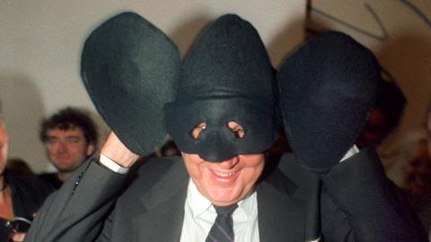 Sichtlich amüsiert setzt der deutsche Bundesaußenminister Hans-Dietrich Genscher (FDP) eine mit übergroßen Ohren ausgestattete "Genschman-Maske" auf. Die Maske wurde ihm am 23. September 1989 beim "Tag der offenen Tür" vom "Genschman-Fanclub" in der Bonner Villa Hammerschmidt übergeben.