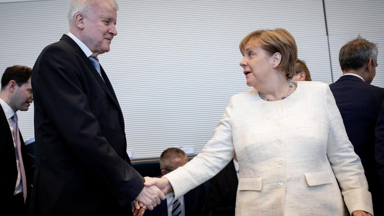 Horst Seehofer (CSU), Bundesminister des Innern, für Bau und Heimat, und Bundeskanzlerin Angela Merkel (CDU) geben sich zu Beginn der Fraktionssitzung der CDU/CSU Fraktion im Bundestag die Hand. Horst Seehofer (CSU), Bundesminister des Innern, für Bau und Heimat, und Bundeskanzlerin Angela Merkel (CDU) geben sich zu Beginn der Fraktionssitzung der CDU/CSU Fraktion im Bundestag die Hand.