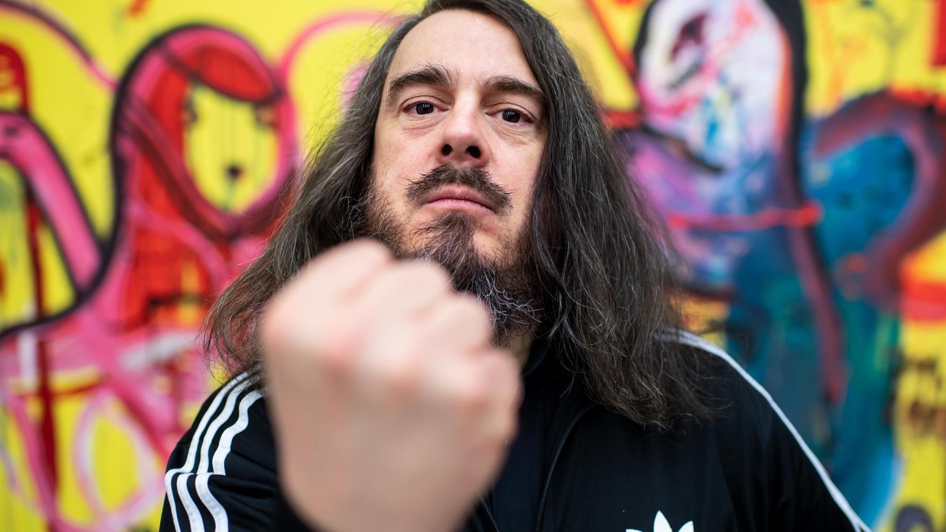 Jonathan Meese hält die geballte Faust in die Kamera. Jonathan Meese hält die geballte Faust in die Kamera.