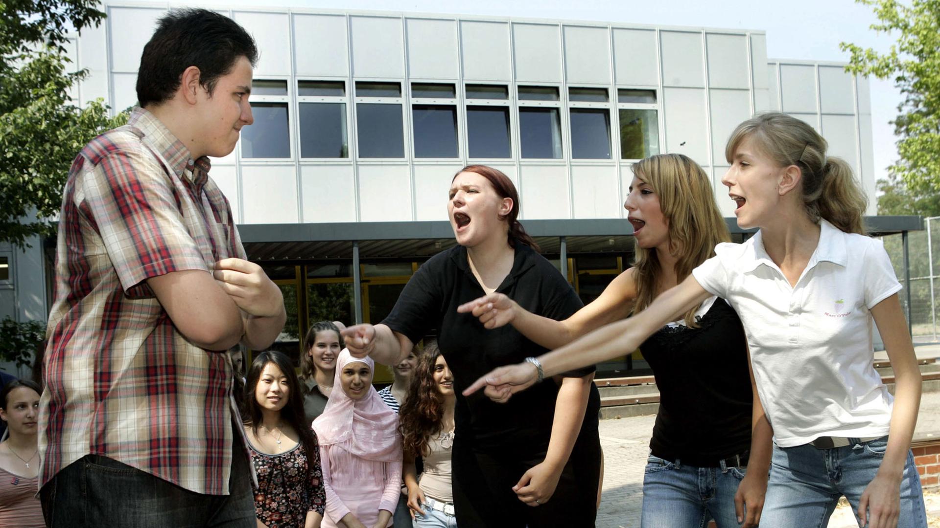 Schülerinnen der Liebig-Schule in Frankfurt am Main beschimpfen in einer gespielten Szene lautstark einen "Agressor" (l). Schülerinnen der Liebig-Schule in Frankfurt am Main beschimpfen in einer gespielten Szene lautstark einen "Agressor" (l).