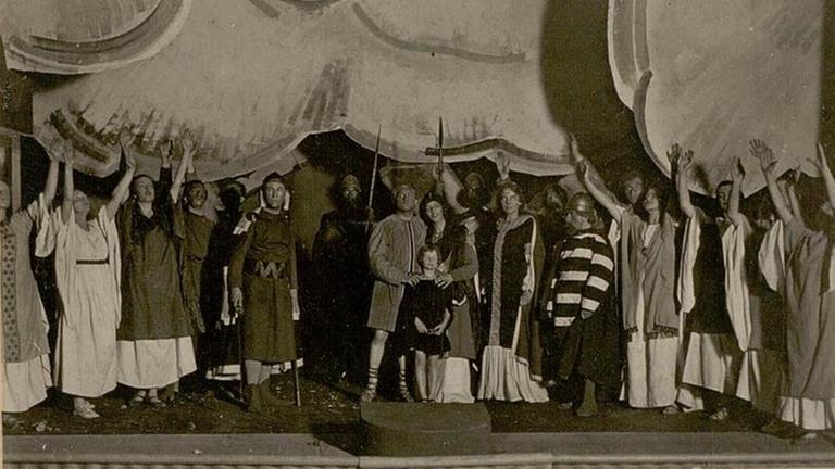 Schwarzweißaufnahme von 1920: Darsteller der Händel-Oper "Rodelinde" stehen in Kostümen zum Schlussbild auf der Bühne versammelt.