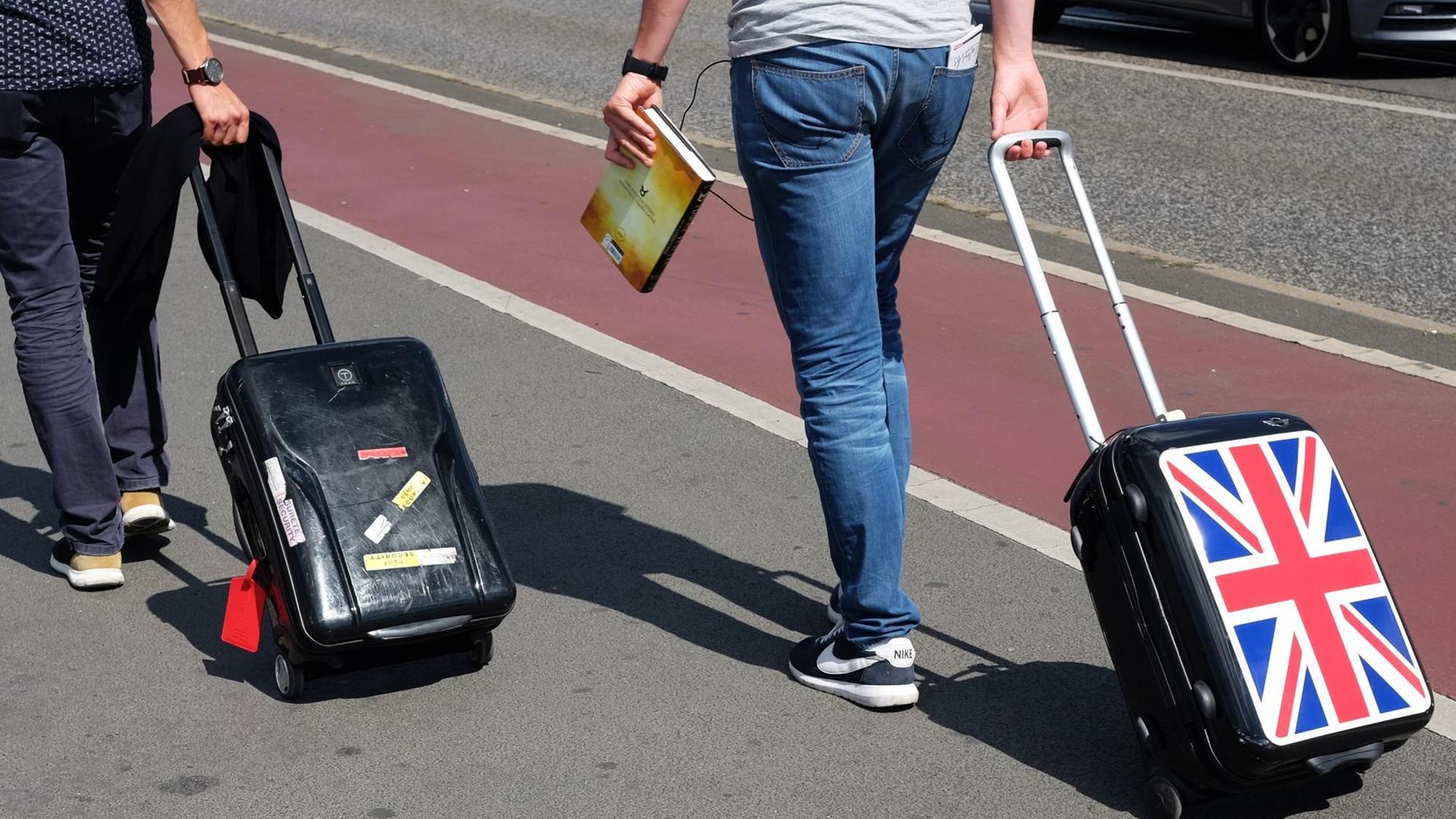 Touristen ziehen auf der Warschauer Straße in Berlin ihre Koffer hinter sich her. Auf einem Rollkoffer ist die britische Fahne zu sehen. Touristen ziehen auf der Warschauer Straße in Berlin ihre Koffer hinter sich her. Auf einem Rollkoffer ist die britische Fahne zu sehen.