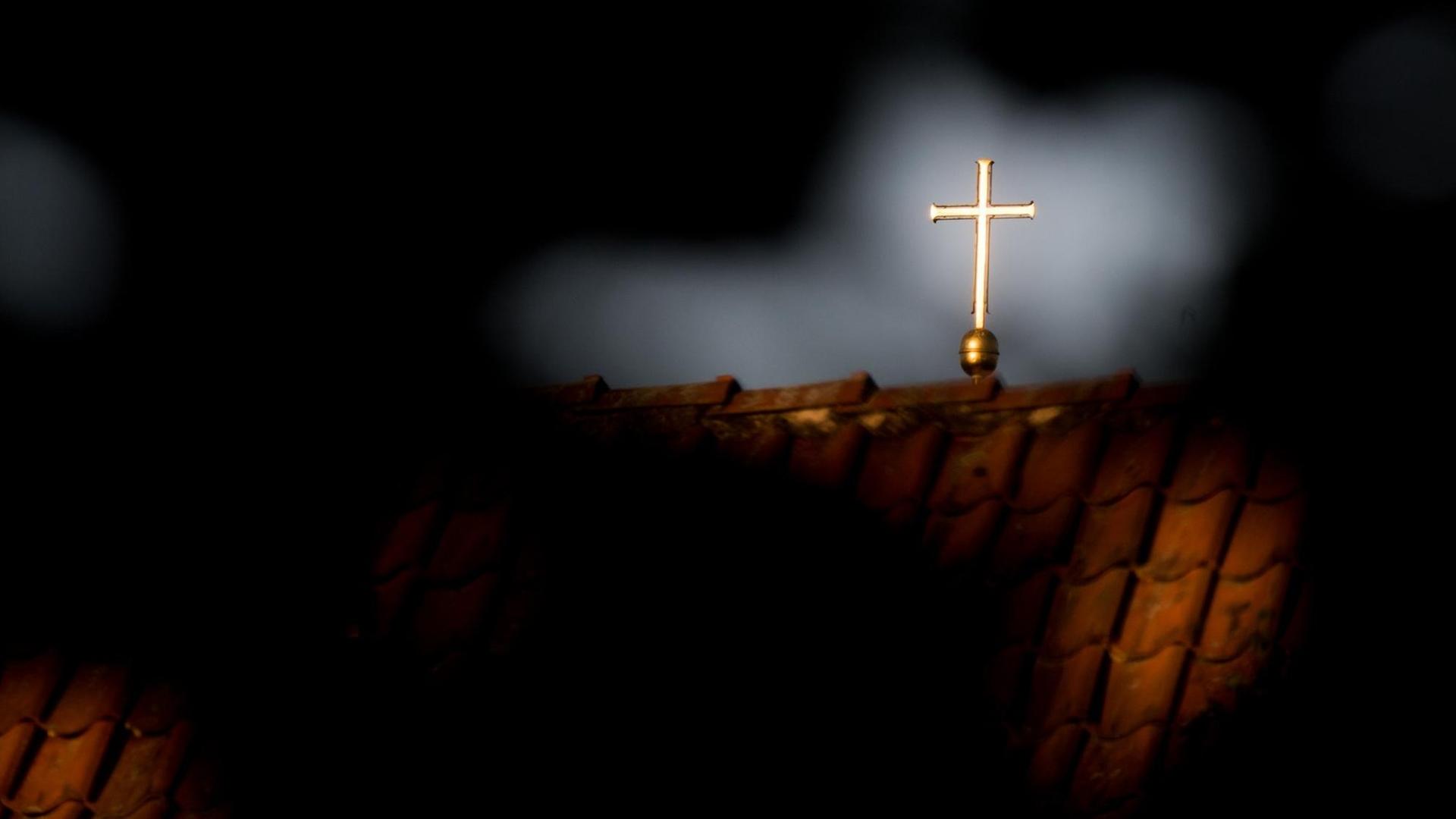 Durch das Geäst eines Baumes ist ein leuchtendes Kreuz zu erkennen. Durch das Geäst eines Baumes ist ein leuchtendes Kreuz zu erkennen.