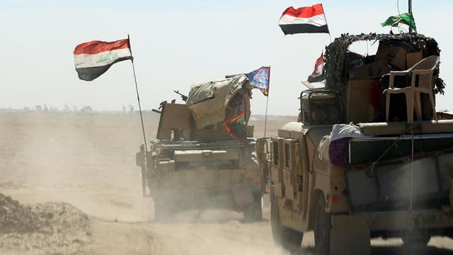 Irakische Streitkräfte am 16. Oktober bei Vorbereitungen südlich von Mossul, zwei Fahrzeuge des Militärs fahren mit irakischen Flagge eine Straße entlang.