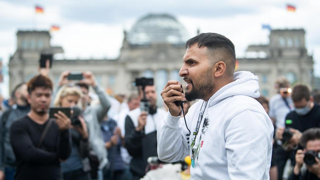 Attila Hildmann, veganer Kochbuchautor und Unternehmer, spricht bei der Abschluss-Kundgebung einer Demonstration gegen die Corona-Politik der Bundesregierung in Berlin; im Hintergrund zu sehen: der Reichstag.