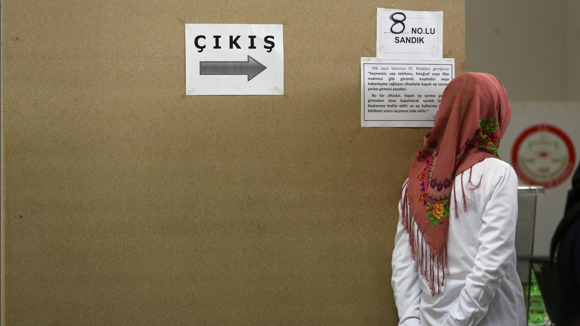 Eine Türkin steht in Dortmund (Nordrhein-Westfalen) in einem türkischen Wahllokal neben einem Schild "Cikis", das türkische Wort für "Ausgang". Eine Türkin steht in Dortmund (Nordrhein-Westfalen) in einem türkischen Wahllokal neben einem Schild "Cikis", das türkische Wort für "Ausgang".