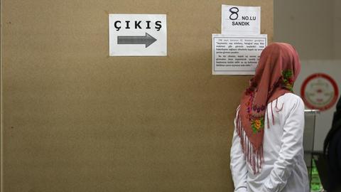 Eine Türkin steht in Dortmund (Nordrhein-Westfalen) in einem türkischen Wahllokal neben einem Schild "Cikis", das türkische Wort für "Ausgang".