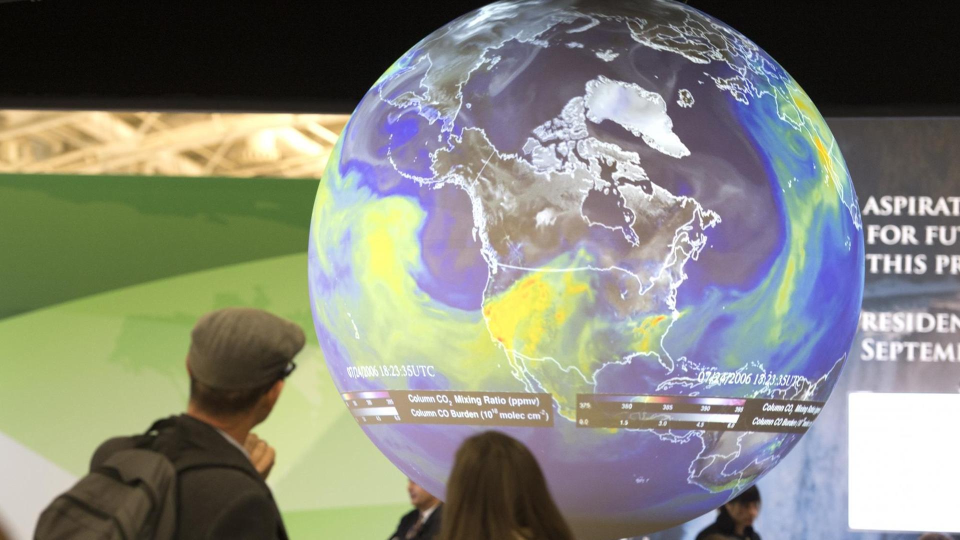 Menschen sehen sich den Globus bei der Klimakonferenz in Paris an. Menschen sehen sich den Globus bei der Klimakonferenz in Paris an.