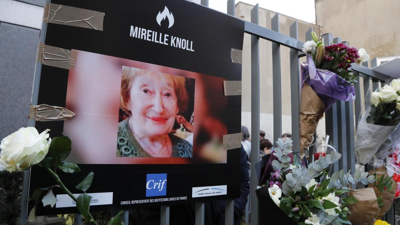 Das Bild zeigt ein Foto von Mireille Knoll und Blumen am Zaun vor dem Haus, wo sie in Paris gelebt hat und ermordet wurde. Das Bild zeigt ein Foto von Mireille Knoll und Blumen am Zaun vor dem Haus, wo sie in Paris gelebt hat und ermordet wurde.