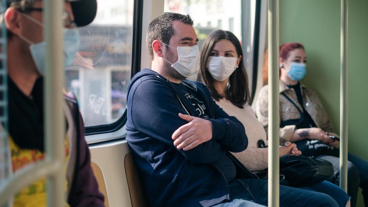 Einige Menschen sitzen mit Mundschutz in der Straßenbahn in Hannover. Einige Menschen sitzen mit Mundschutz in der Straßenbahn in Hannover.