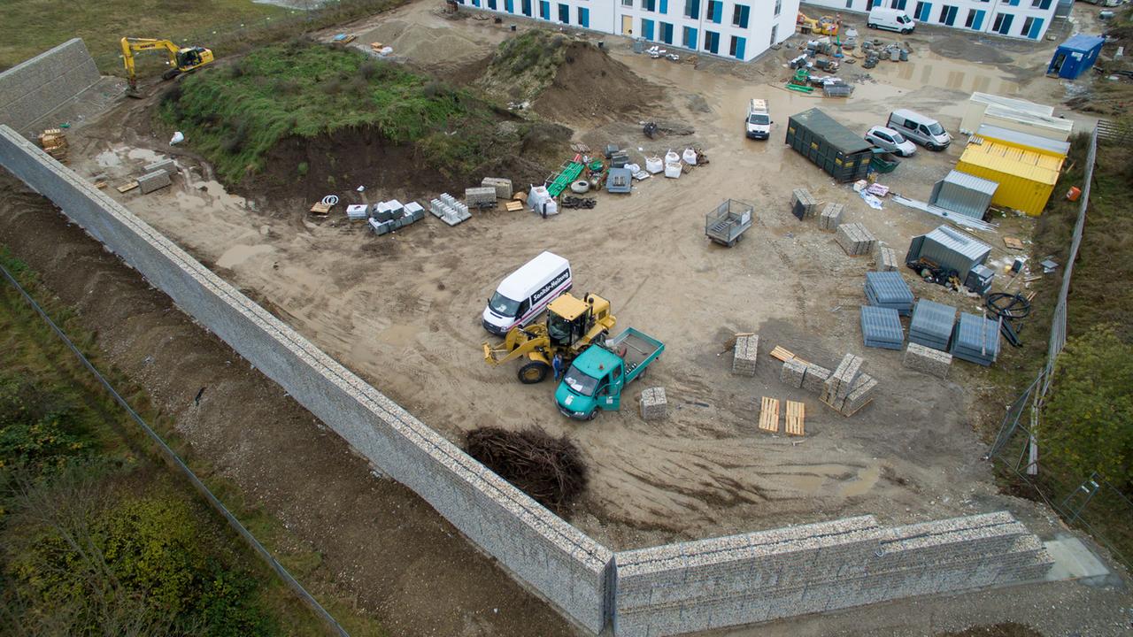 Eine Steinmauer ist am 7.11.2016 in München auf der Baustelle für eine Flüchtlingsunterkunft zu sehen. Anwohner hatten die Mauer als Lärmschutz im Stadtteil Neuperlach durchgesetzt. Eine Steinmauer ist am 7.11.2016 in München auf der Baustelle für eine Flüchtlingsunterkunft zu sehen. Anwohner hatten die Mauer als Lärmschutz im Stadtteil Neuperlach durchgesetzt.