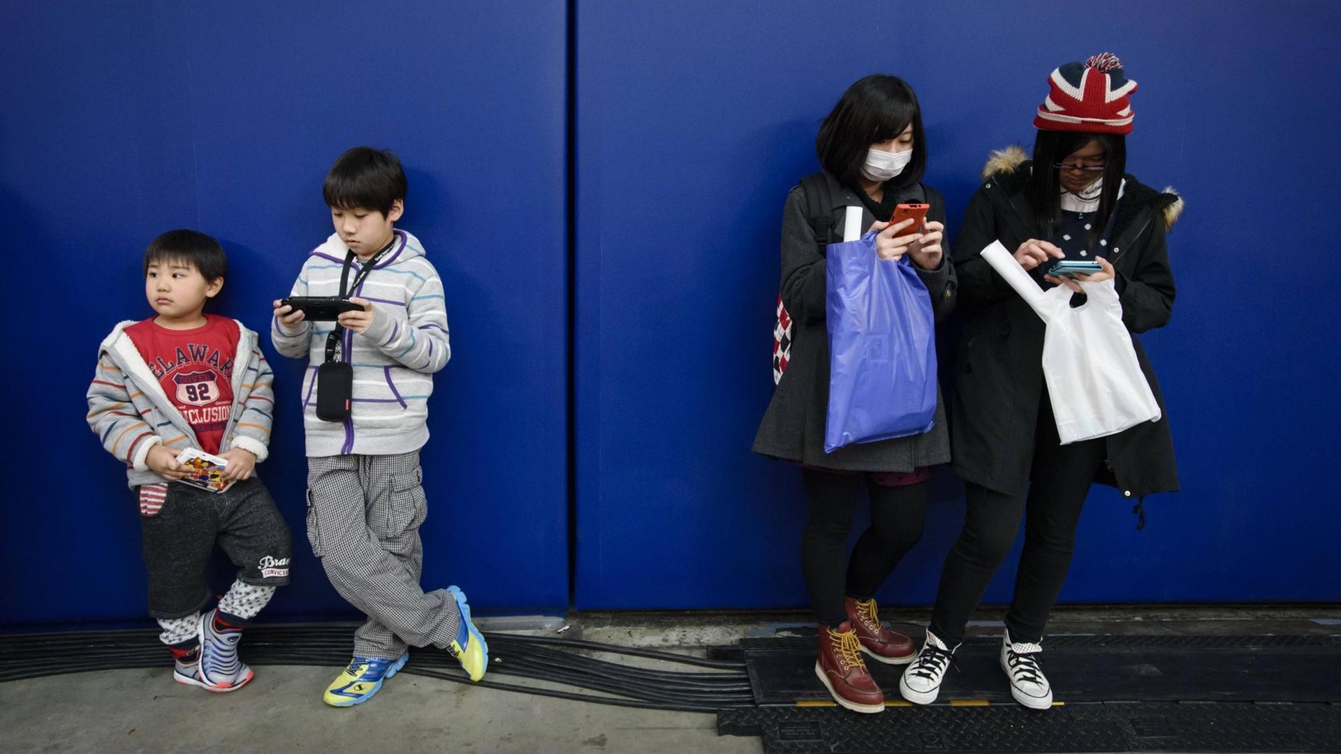 Vier Kinder vertreiben sich die Zeit mit Spielen auf ihren Mobiltelefonen. Vier Kinder vertreiben sich die Zeit mit Spielen auf ihren Mobiltelefonen.