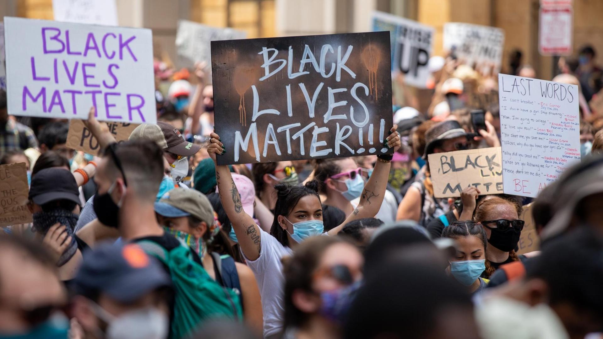 Protestierende halten Plakate mit der Aufschrift "Black Lives Matter" in die Höhe. Protestierende halten Plakate mit der Aufschrift "Black Lives Matter" in die Höhe.