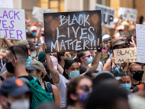 Protestierende halten Plakate mit der Aufschrift "Black Lives Matter" in die Höhe.