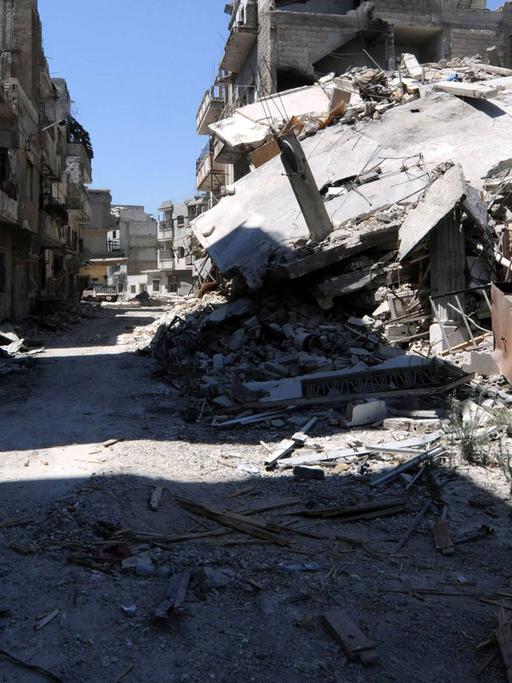 Ein Journalist läuft mit einer Kamera eine zerstörte Straße in der Homs-Provinz in Syrien lang