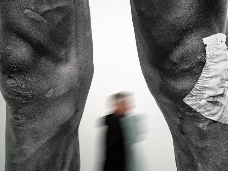 Ein Besucher geht in der Foto-Gruppenausstellung "Mythos Tour de France" an dem Bild "Legs From The Peleton/Mauricio Soler von Timm Kölln vorbei.
