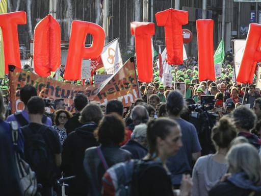 Menschen ziehen durch die Brüsseler Innenstadt. Einige von ihnen halten große Buchstaben in die Höhe, die die Forderung ergeben: Stop TTIP.