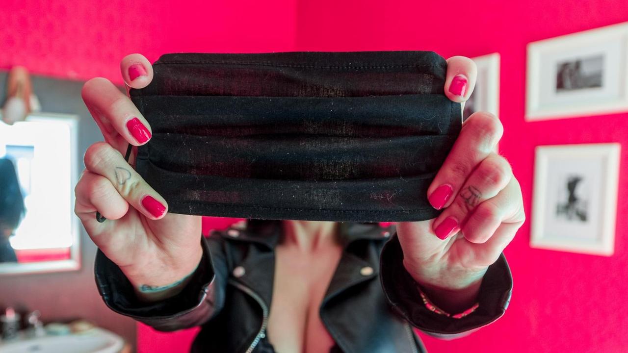 Eine Sexarbeiterin verdeckt mit einer Mund-Nasen-Maske an ihrem Arbeitsplatz ihr Gesicht. Eine Sexarbeiterin verdeckt mit einer Mund-Nasen-Maske an ihrem Arbeitsplatz ihr Gesicht.