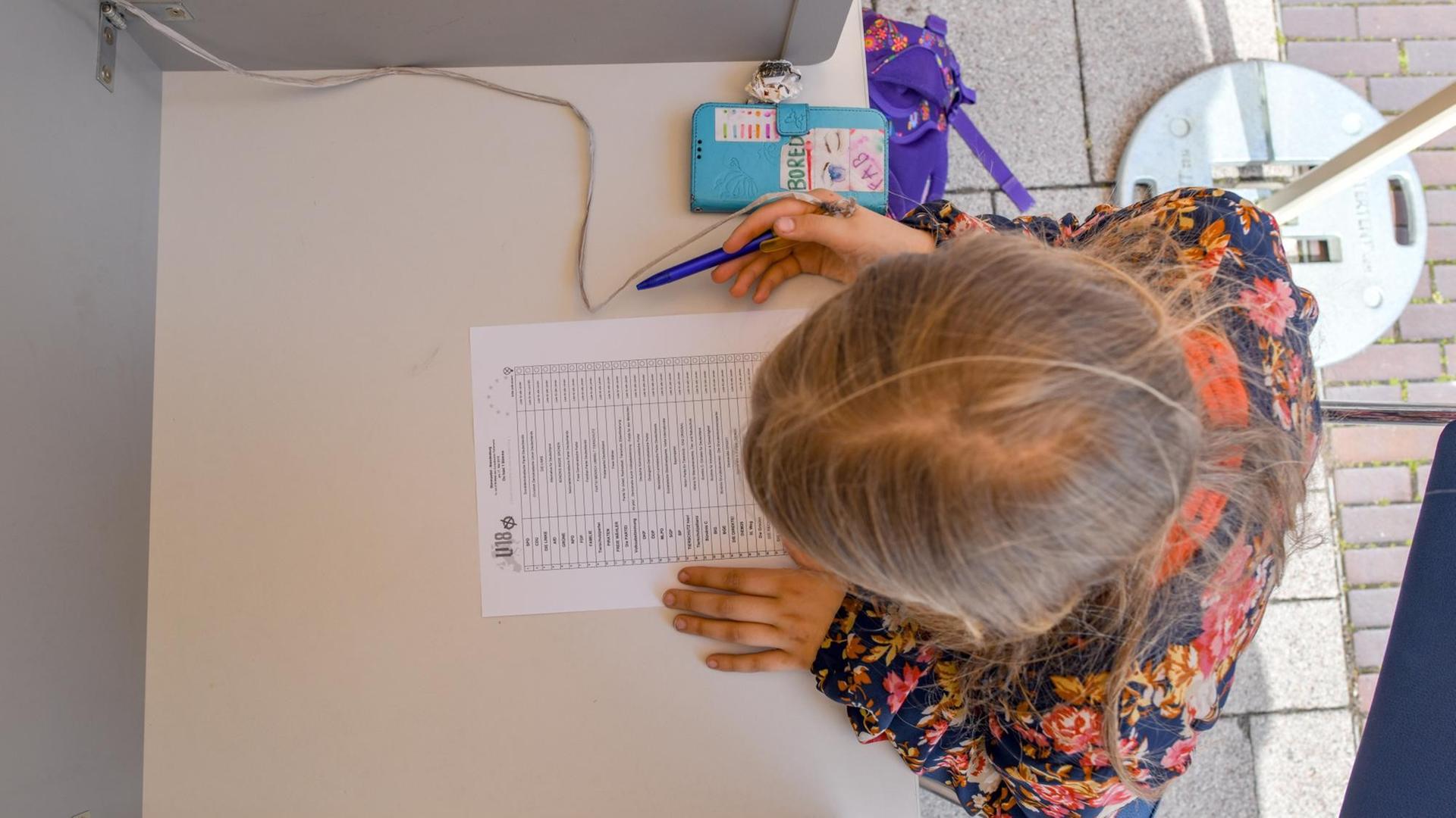 Ein elfjähriges Mädchen sitzt bei der U18-Europawahl 2019 in einer Wahlkabine in Brandenburg. Ein elfjähriges Mädchen sitzt bei der U18-Europawahl 2019 in einer Wahlkabine in Brandenburg.
