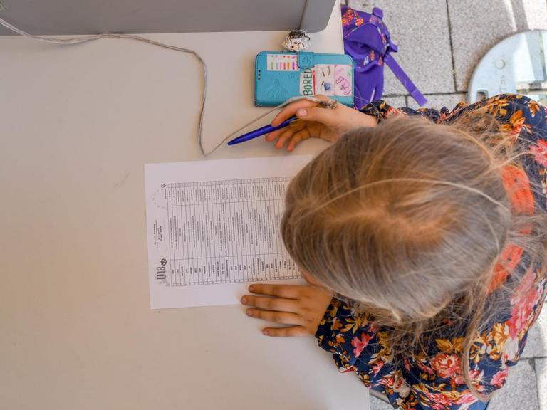 Ein elfjähriges Mädchen sitzt bei der U18-Europawahl 2019 in einer Wahlkabine in Brandenburg.