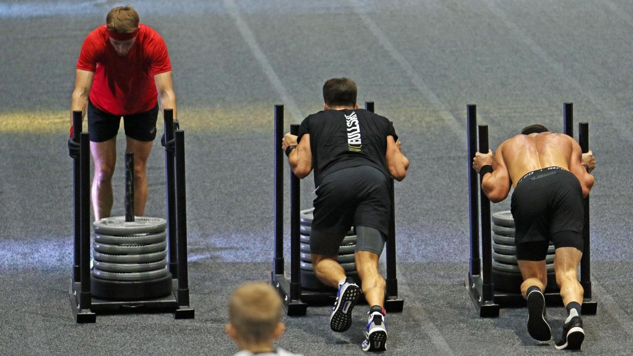 Drei Teilnehmer schieben Gewichte im Rahmen des Fitness-Wettbewerbs Hyrox.