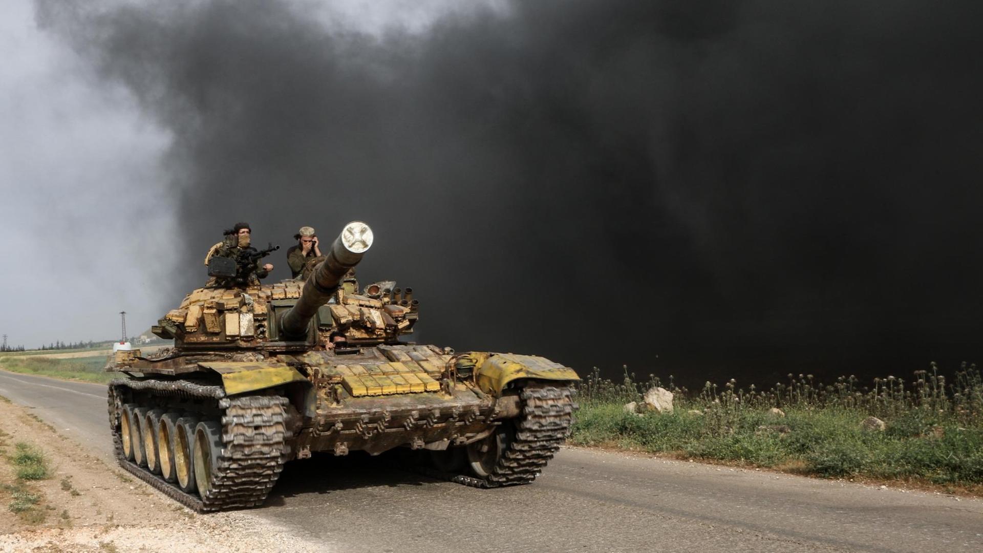 Syrien, Kafr Nabudah: Syrische Oppositionskämpfer fahren auf einer Straße mit einem Panzer an die Front in der Provinz Hama. Syrien, Kafr Nabudah: Syrische Oppositionskämpfer fahren auf einer Straße mit einem Panzer an die Front in der Provinz Hama.